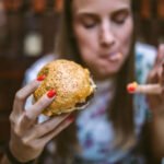 Gourmand Girl Eating Tasty Hamburger at Fast Food Restaurant istockphoto 1055590912 612x612 1 - Lifestyle